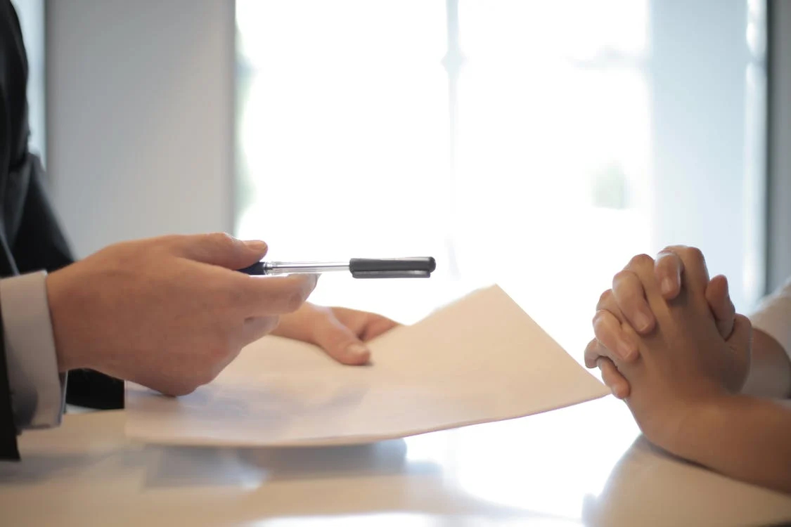 Persona entregando boli y contrato de arrendamiento a otra